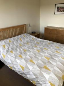 a bedroom with a bed with a yellow and white comforter at Apartment 76 in Kirkwall
