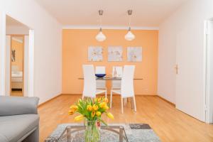 ein Wohnzimmer mit einem Tisch mit Stühlen und einer Vase aus Blumen in der Unterkunft Appartements Ferchergasse in Wien