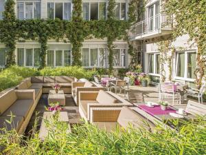 a patio with tables and chairs and a building at Boutique Hotel Atrium München in Munich