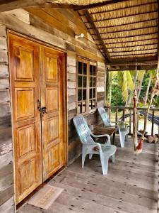 a porch of a wooden cabin with two chairs and a door at Beachfront Hut Upstairs Astra - Beach Shack Chalet in Tioman Island