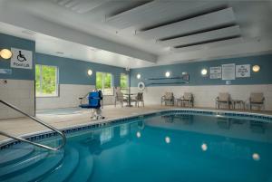 a swimming pool in a gym with chairs and tables at Holiday Inn Express Independence - Kansas City by IHG in Independence