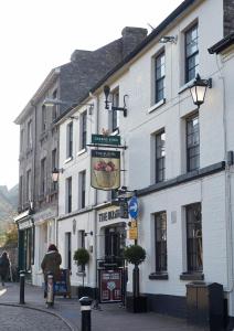 a white building on a city street with a person on a bike at The Bushel by Greene King Inns in Bury Saint Edmunds