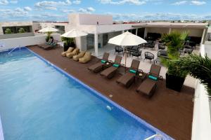 a swimming pool with chairs and umbrellas on a building at Holiday Inn Express & Suites - Playa del Carmen by IHG in Playa del Carmen
