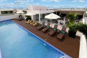 a swimming pool with chairs and umbrellas on a building at Holiday Inn Express & Suites - Playa del Carmen, an IHG Hotel in Playa del Carmen