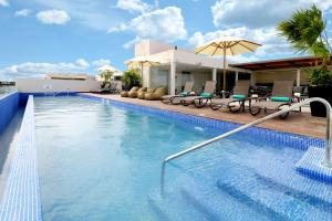 una piscina con sillas y sombrilla en Holiday Inn Express & Suites - Playa del Carmen, an IHG Hotel en Playa del Carmen