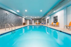 a swimming pool with orange chairs in a building at Holiday Inn Express Hotel and Suites Petersburg - Fort Lee, an IHG Hotel in Petersburg