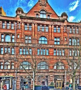 un gran edificio de ladrillo con un árbol delante de él en ABode Manchester en Mánchester