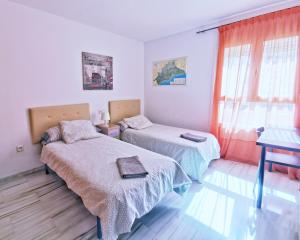 1 dormitorio con 2 camas, ventana y mesa en Neptuno Apartment: Sun, beach and relax in Huelin, en Málaga