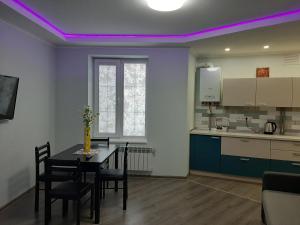 a kitchen with a table and chairs and a purple lighting at Люкс 2 in Uzhhorod
