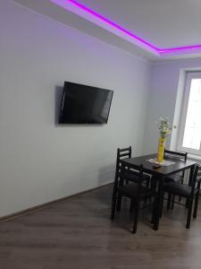 a dining room with a table and a tv on a wall at Люкс 2 in Uzhhorod