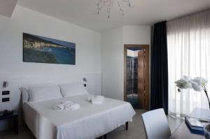 a white bedroom with a large white bed and a table at Hotel Belvedere in Torre dell'Orso