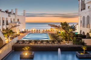 a hotel pool with chairs and the ocean in the background at Belmar Spa & Beach Resort in Lagos