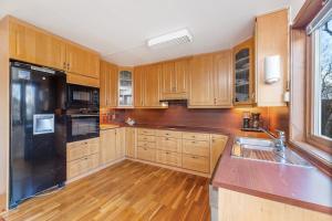 a kitchen with wooden cabinets and a black refrigerator at Goldin in Kautokeino