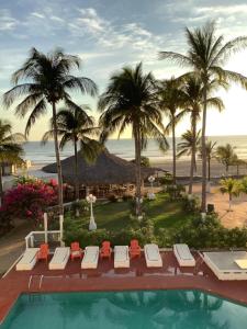 a resort with a pool and palm trees and the beach at Hotel Arista Bugambilias in Puerto Arista