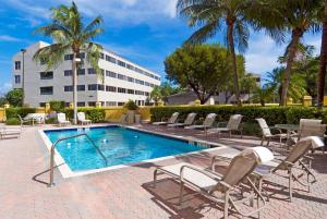 a swimming pool with chairs and a building at Holiday Inn Express Hotel & Suites Kendall East-Miami, an IHG Hotel in Kendall