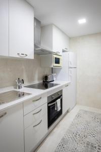 a white kitchen with a sink and a microwave at Apartamentos BCL Playa Albir in Albir