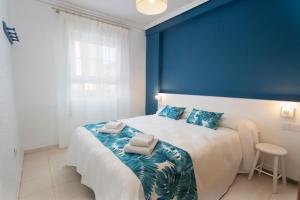 Dormitorio azul con cama blanca y paredes azules en Apartamentos BCL Playa Albir, en Albir