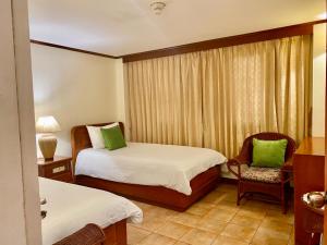 una camera d'albergo con due letti e una sedia di Surin Bay Inn a Surin Beach
