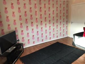 a living room with pink pineapple wallpaper on the wall at Thurso Self Catering Pet Friendly Holiday Lets in Thurso