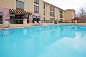 ein großer Pool mit Stühlen und ein Gebäude in der Unterkunft Holiday Inn Express Hotel & Suites Charlotte Airport-Belmont, an IHG Hotel in Belmont