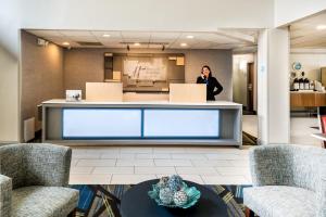 a man standing behind a counter in a lobby at Holiday Inn Express & Suites Charlotte Arpt-Belmont by IHG in Belmont