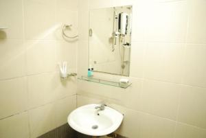 a white bathroom with a sink and a mirror at Lacomme Inn in Kuala Lumpur