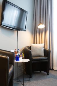 a living room with two chairs and a tv on the wall at Hotell Leksand in Leksand