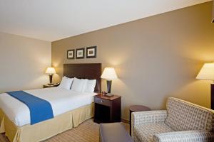 a hotel room with a bed and a chair at Holiday Inn Express & Suites Malone, an IHG Hotel in Malone