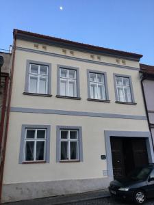 une maison blanche avec des fenêtres et une voiture garée devant dans l'établissement Apartmán Český Ráj, à Jičín