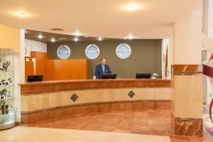 a man standing at a counter in a lobby at IFA Altamarena by Lopesan Hotels in Morro del Jable