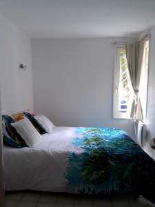 ein Bett in einem weißen Zimmer mit einem Fenster in der Unterkunft Vallon des sources digne les bains in Digne-les-Bains