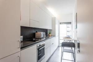 uma cozinha com armários brancos e um forno com placa de fogão em FLH Expo Modern Flat with Balcony em Lisboa