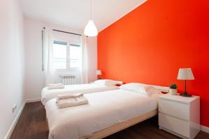 Duas camas num quarto com uma parede laranja em FLH Expo Modern Flat with Balcony em Lisboa