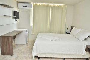 a bedroom with a bed and a desk and a window at Carvalho's Hotel in Palmas