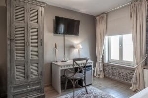 a bedroom with a desk and a tv on the wall at Auberge l'Entrecôte in Kluisbergen