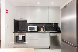 una cucina con armadi bianchi e frigorifero in acciaio inossidabile di FLH Liberdade Terrace Apartment a Lisbona