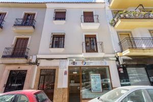 a white building with cars parked in front of it at Apartamentos Baiti Ronda in Ronda