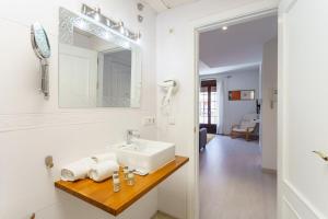 a white bathroom with a sink and a mirror at Apartamentos Baiti Ronda in Ronda +66 photos