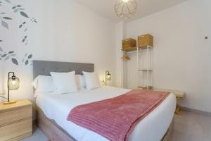 a bedroom with a large white bed with a red blanket at Apartamentos Baiti Ronda in Ronda