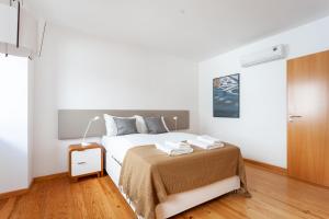 a white bedroom with a bed and a wooden floor at FLH Liberdade Contemporary Flat in Lisbon