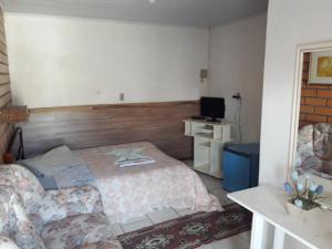 um quarto com uma cama, uma cadeira e uma televisão em Hotel Pousada Casa Nostra em Erechim