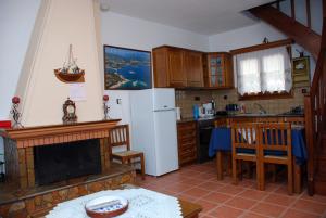 a kitchen with a fireplace and a white refrigerator at Vila Elena 1astoning view in Steni Vala Alonissos