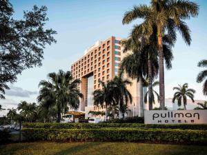 a hotel with palm trees in front of it at Pullman Miami Airport in Miami