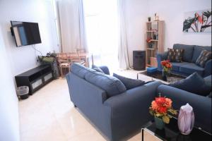  شاليه السعادة في جدة: غرفة معيشة مع أريكة زرقاء وتلفزيون