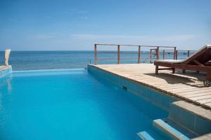 a swimming pool with a bench next to the ocean at B&B Las Playitas in Máncora