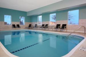 una piscina en una habitación de hotel con sillas y mesas en Holiday Inn Express Pekin - Peoria Area, an IHG Hotel, en Pekin Heights