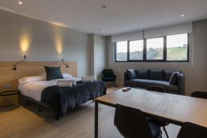 a bedroom with a bed and a couch and a table at Milimara Suites in San Sebastián