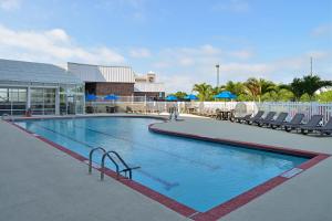 une grande piscine avec des chaises et un bâtiment dans l'établissement Holiday Inn Express & Suites - Ocean City, an IHG Hotel, à Ocean City