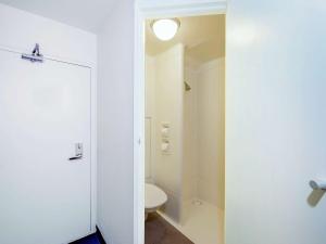 a bathroom with a toilet and a white door at ibis Budget - Enfield in Sydney