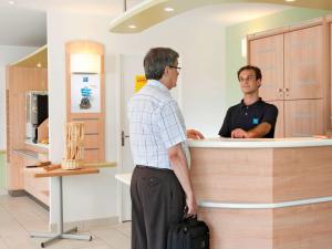 two men standing at a counter in a store at ibis budget Mainz Hechtsheim in Mainz